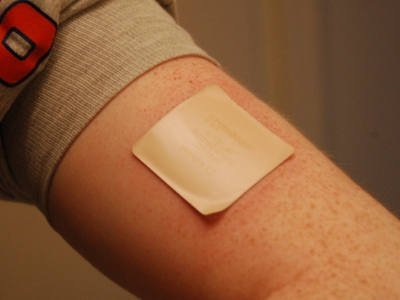 man in a sweater using a nicotine patch on arm