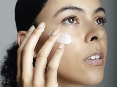 woman with fair skin applying cream on her cheeks